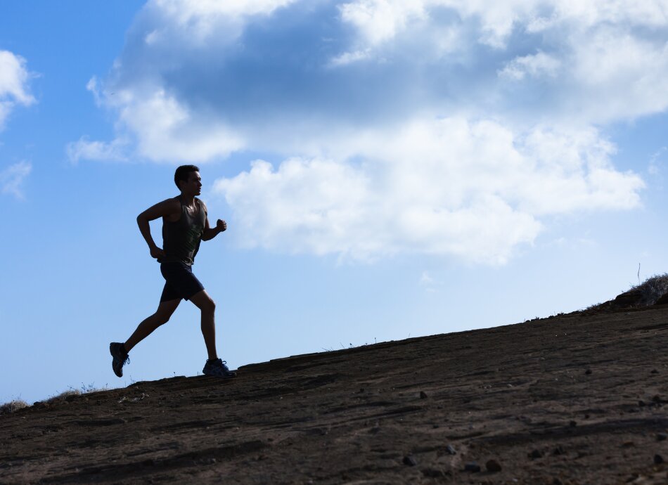 Silhouetted man running up a hill