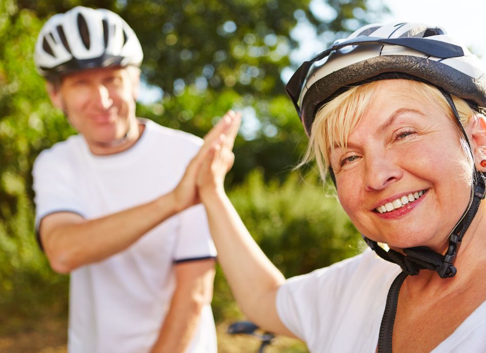 Older couple high five wearing cycle helmets