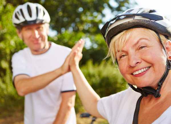 Older couple high five wearing cycle helmets