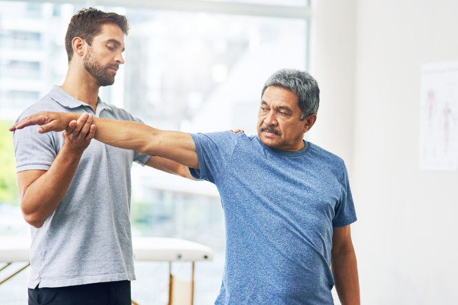 Physio assists man with stretching exercises