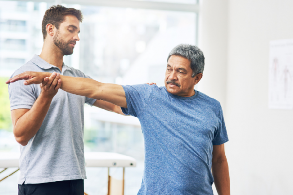 Physiotherapist helps man with arm exercises