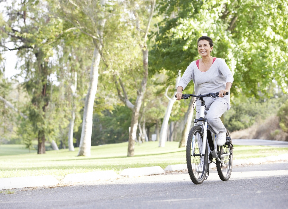 Smiling woman riding bike beside park 