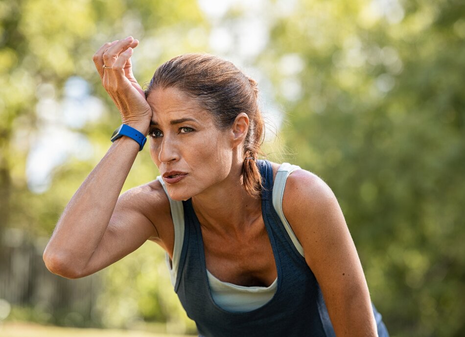 Tired, out of breath woman stops while exercising outdoors