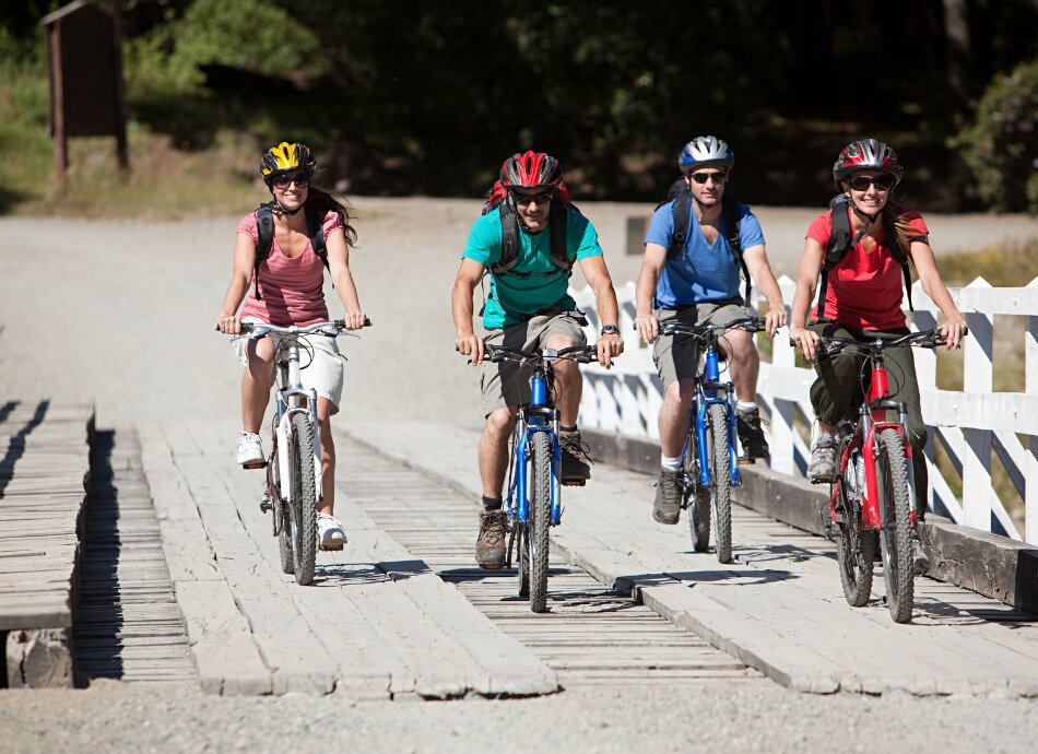 4 people cycling over a wooden bridge