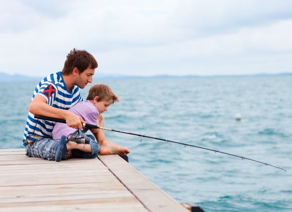 Father and son fishing off a jetty by the sea