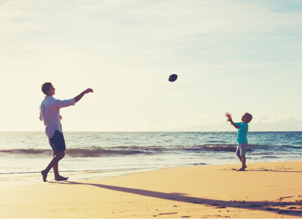 Adult and child throwing and catching a ball on the beach