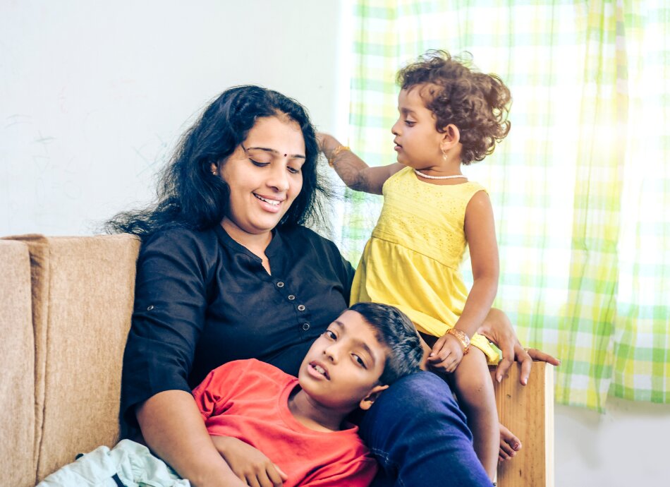 Indian woman with two children sitting on couch 