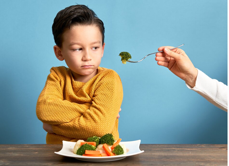 Boy with plate of vegetables refuses to eat