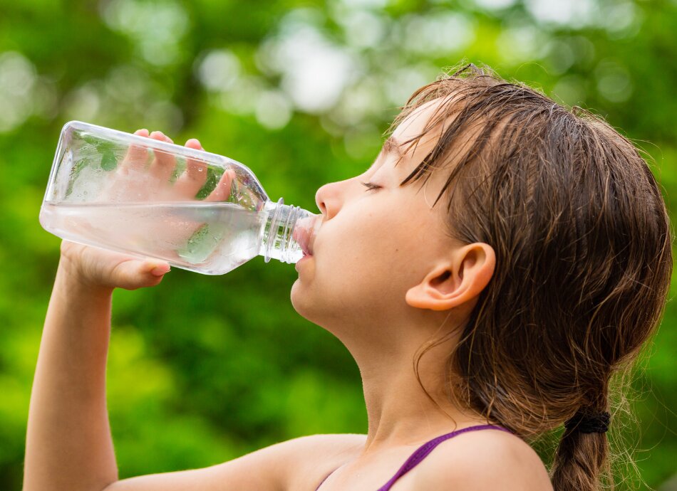 Girl drinking water from plastic bottle
