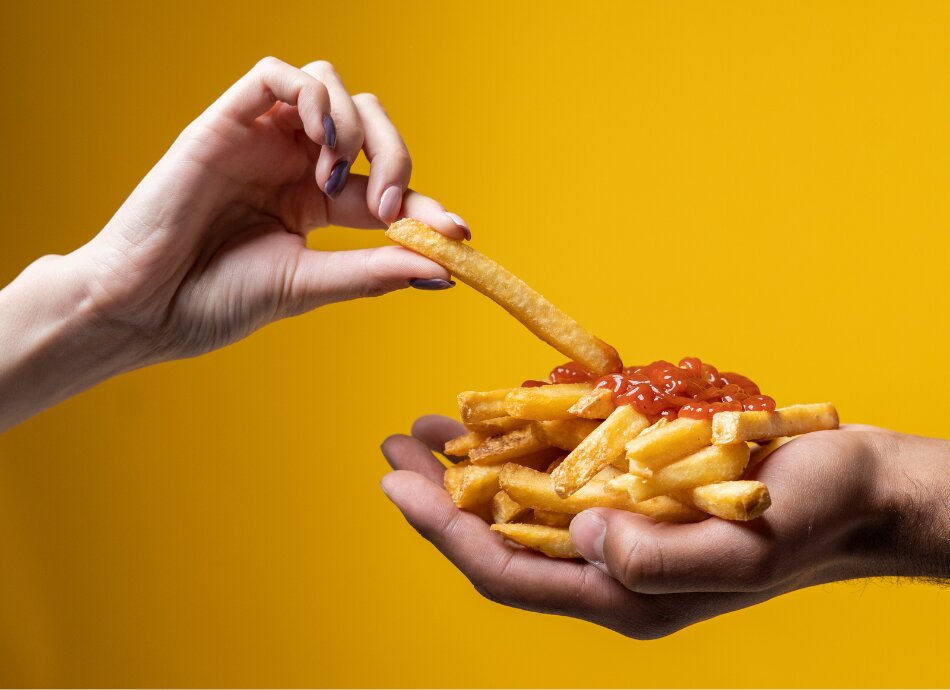 Hand helping themselves to french fries with sauce