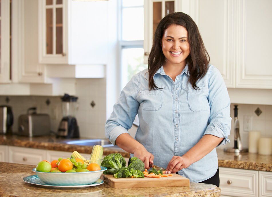 Larger woman chopping vegetables in kitchen