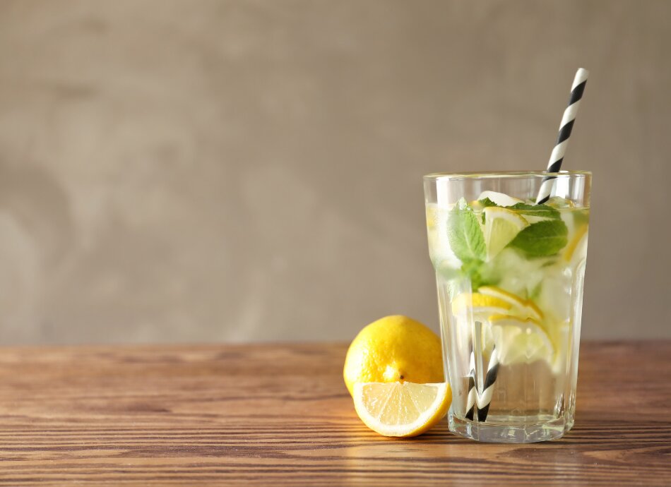 Glass of water with lemon, mint and a straw