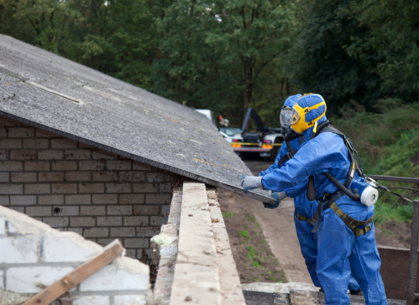 Men in protective clothing removing asbestos from a building