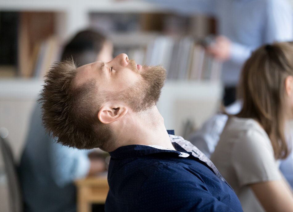 Young man asleep in class with other students