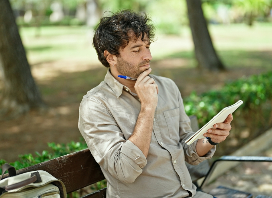 Young man sitting on bench reviewing list