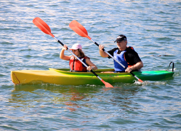 People in double kayak wearing lifejackets and sun hats