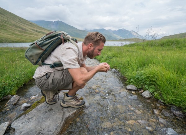 Man drinking water from a stream