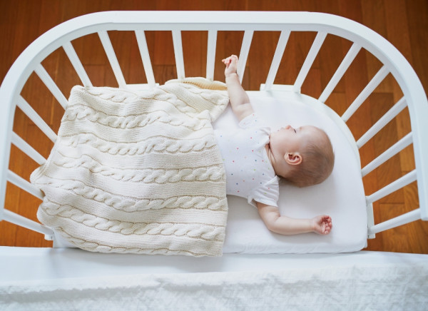 Baby sleeping in 3 sided cot next to parents' bed