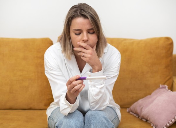 Woman looking at pregnancy test result with mixed feelings