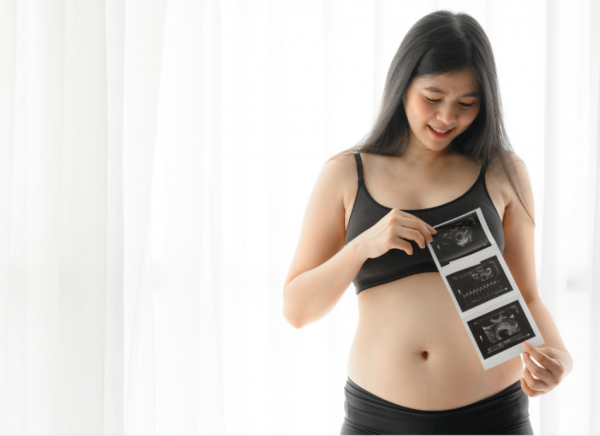 Young pregnant person looking at pregnancy ultrasound printout