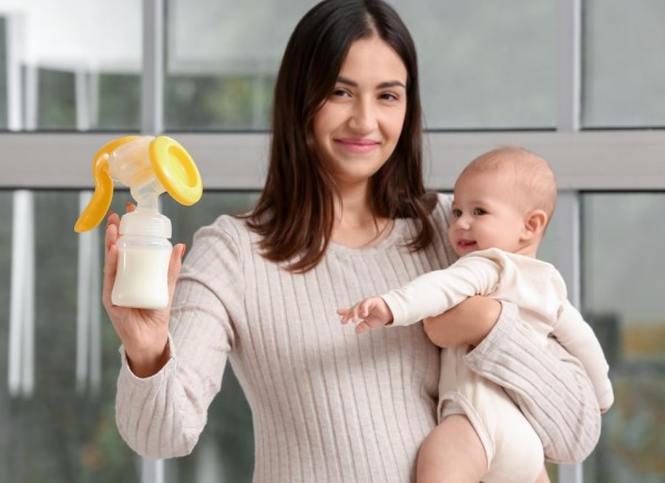 Young woman holding baby and bottle of expressed breast milk
