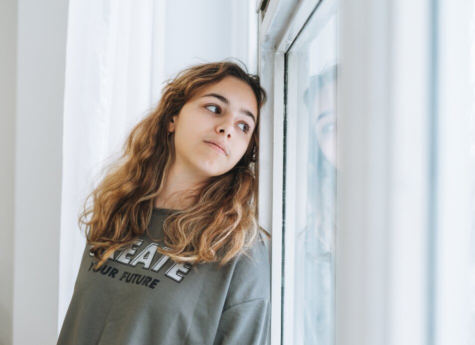 Thoughtful teenager looks out window