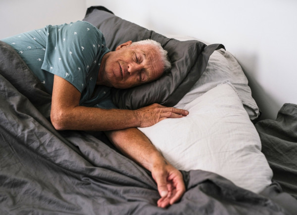 Older man sleeping on his side using two pillows