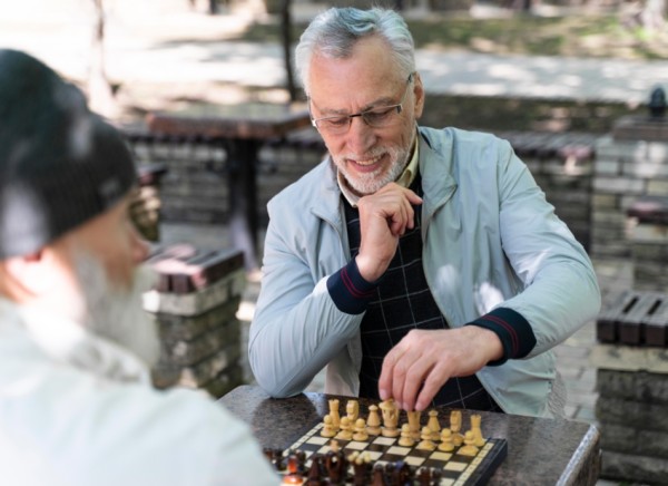 Older men playing chess, one wearing glasses