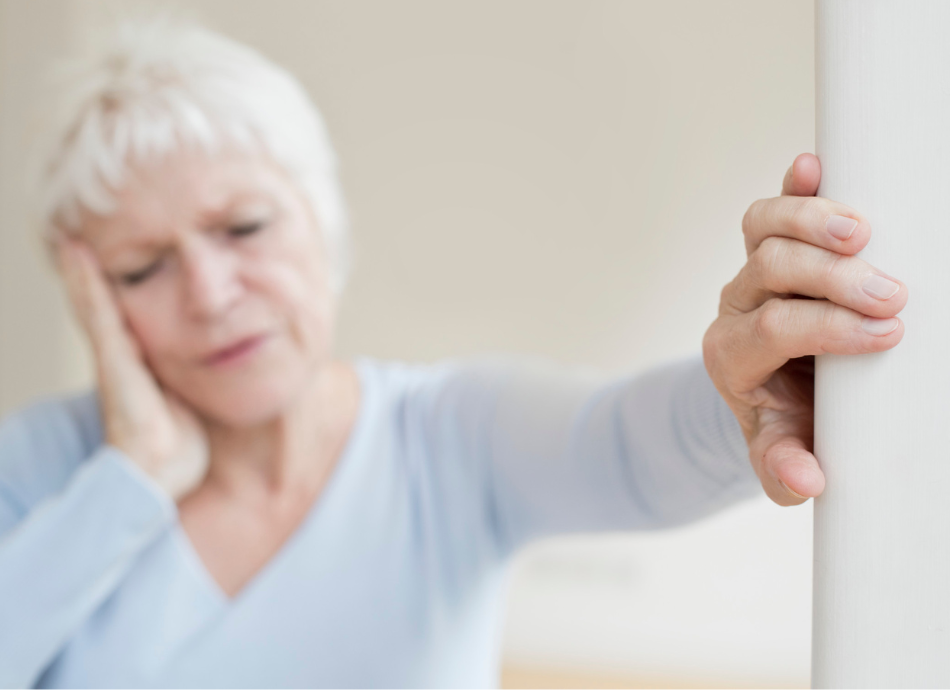 Older woman leaning on wall feeling dizzy