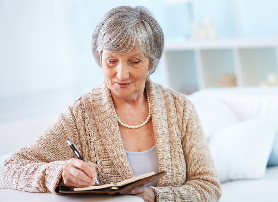 Older woman writing notes in book canva 950x690