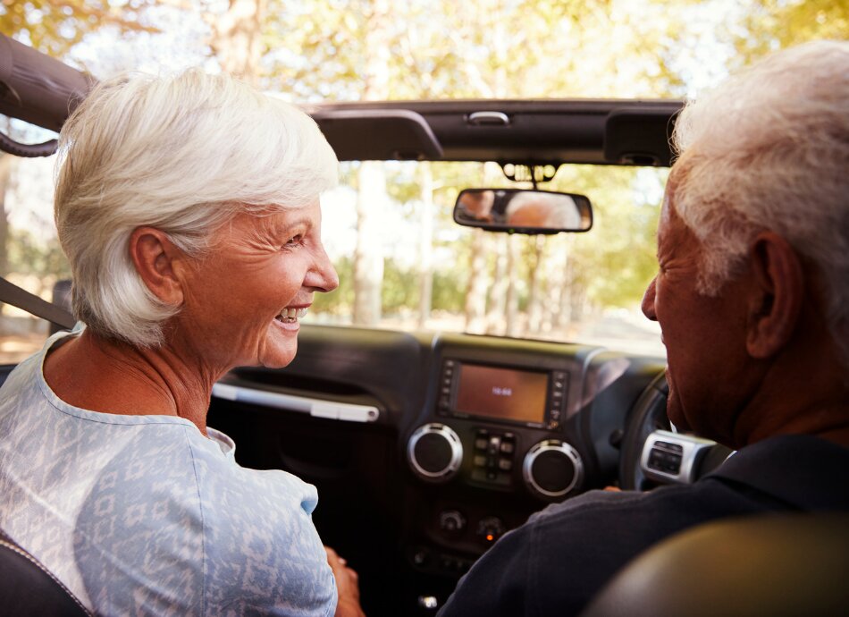 Senior couple smiling at each other while driving in car