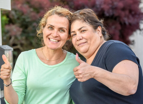 Two smiling women giving thumbs up sign