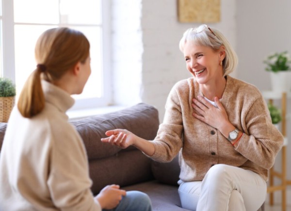 Women sitting on couch facing each other while talking