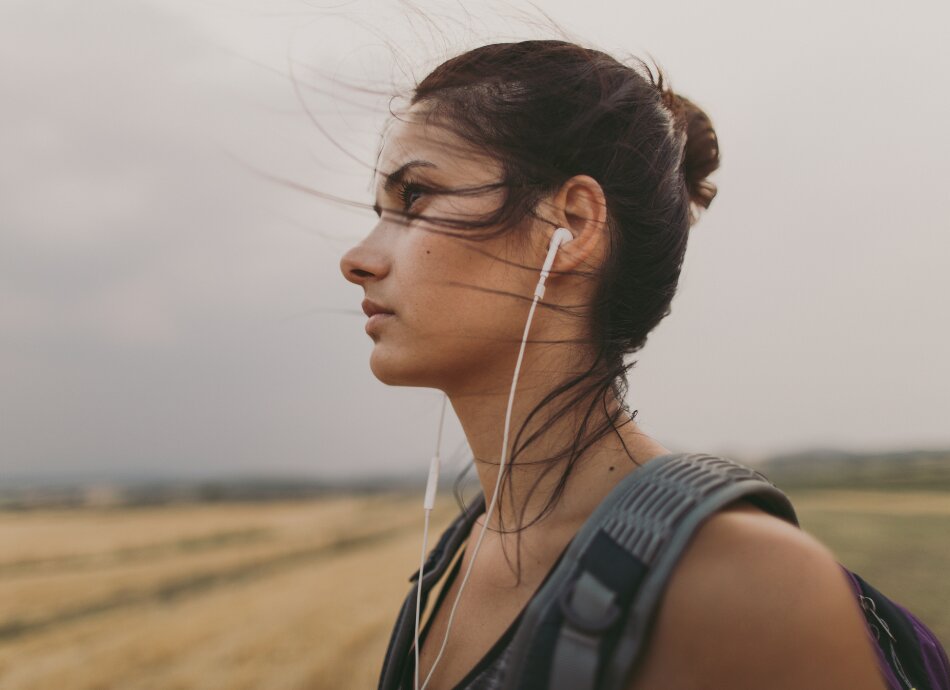 Young woman outdoors wearing ear buds looks determined