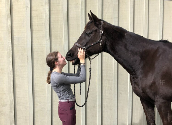 Young woman rubbing noses with horse
