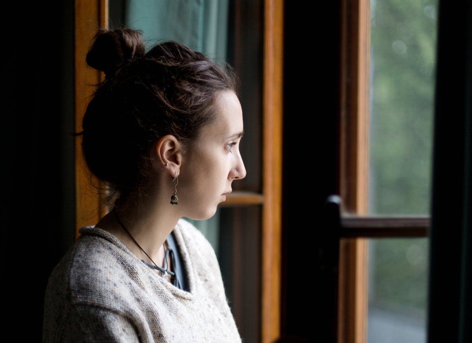 worried young woman looking out window