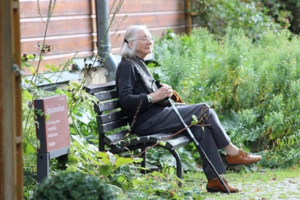 Senior woman resting on a bench in a garden