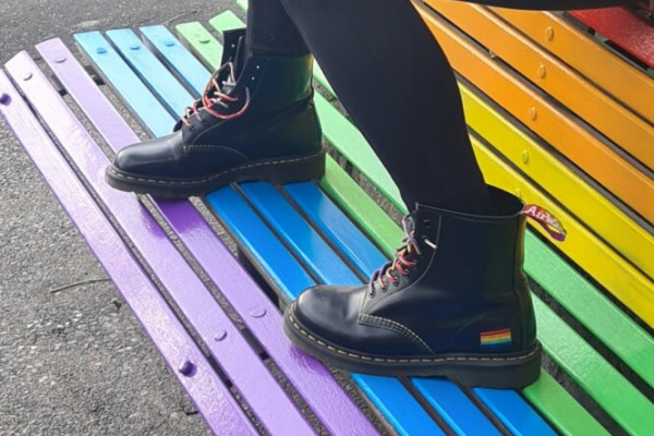 Boots on rainbow pride-painted bench outdoors