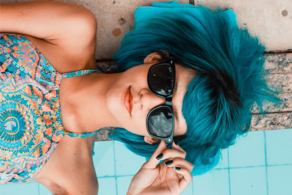 Young woman with blue hair wears sunglasses