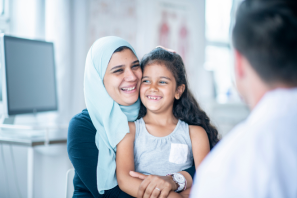 Smiling mother in headscarf holding daughter