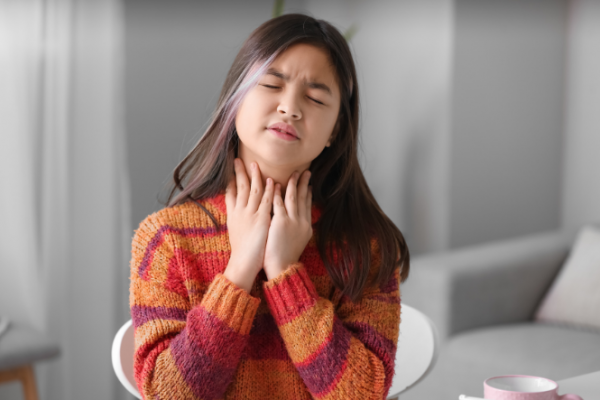 Girl with sore throat holding her neck 