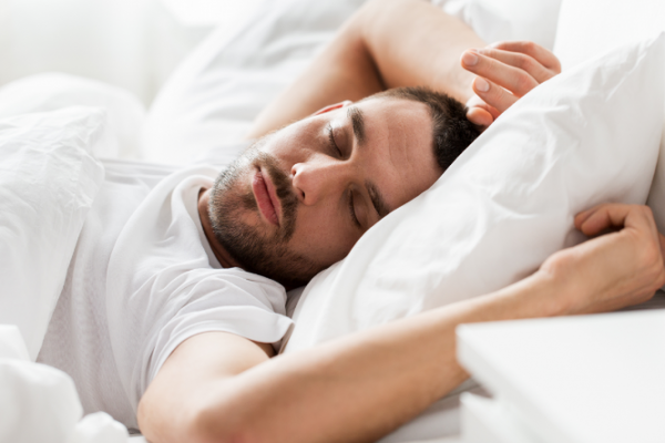 Man sleeping on his back with arms flung up