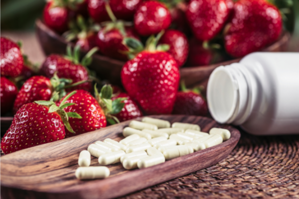 Pills on a wooden board with strawberries