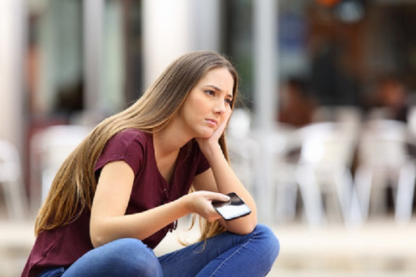 Young woman looking sad and holding phone