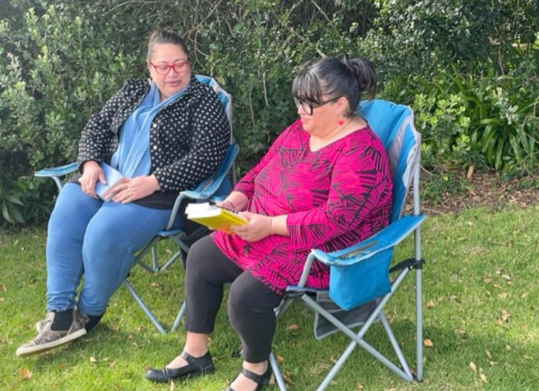 Two friends read books sitting in garden chairs