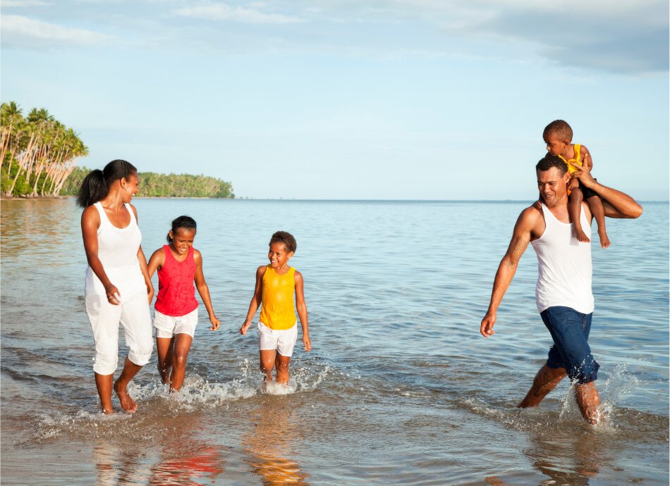 Fijian family of 5 wading in water at the beach