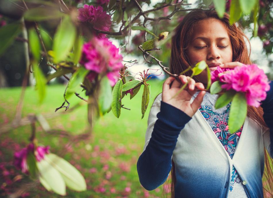 Girl smells pink flowers on tree