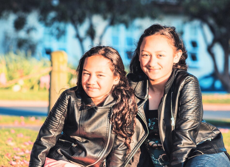 Two Māori sisters smiling under trees
