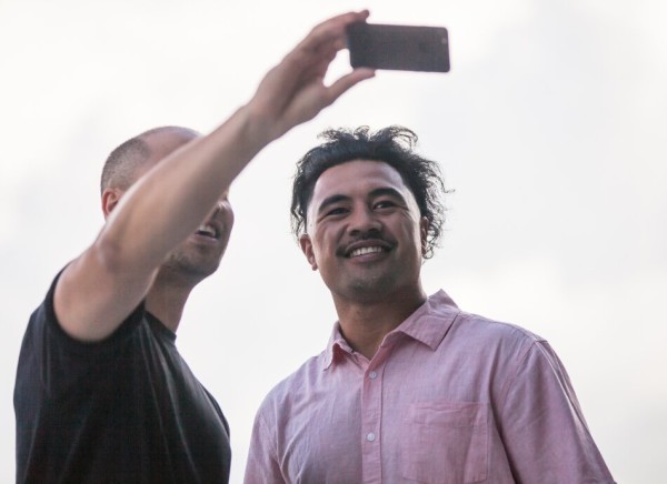 Two men looking at phone or about to record.