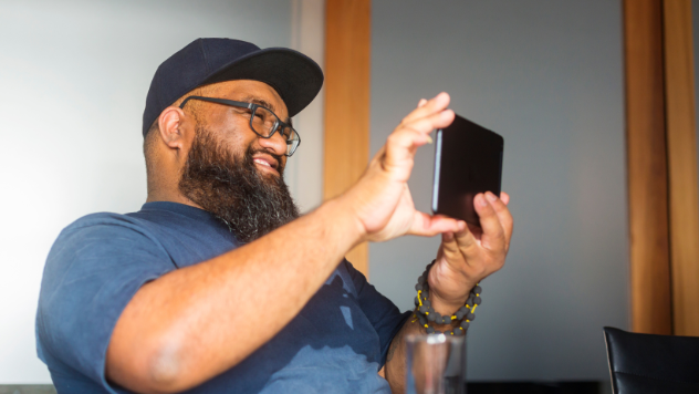 Smiling Pasifika man in cap using tablet
